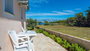 A patio with a stone floor, white plastic chairs, and a table. - Beachside Holiday Home Anamarija (Lozice)