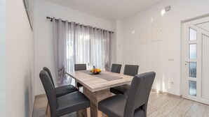 A dining area with a wooden table, six black chairs, and a fruit bowl. - Beachside Holiday Home Anamarija (Lozice)