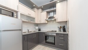 A modern kitchen with grey cabinets, a built-in oven, a microwave, and a coffee maker. - Beachside Holiday Home Anamarija (Lozice)