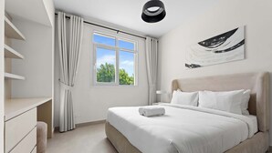 Une chambre moderne avec un grand lit, une table de chevet, une armoire et une fenêtre avec des rideaux.