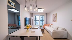 Une chambre d’hôtel moderne dotée d’un coin repas, d’un canapé, d’une télévision et d’une grande fenêtre.
