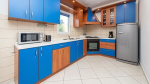 A kitchen with blue cabinets, a microwave, a stove, and a refrigerator. - Beachside Holiday Home Manuela (Lozice)
