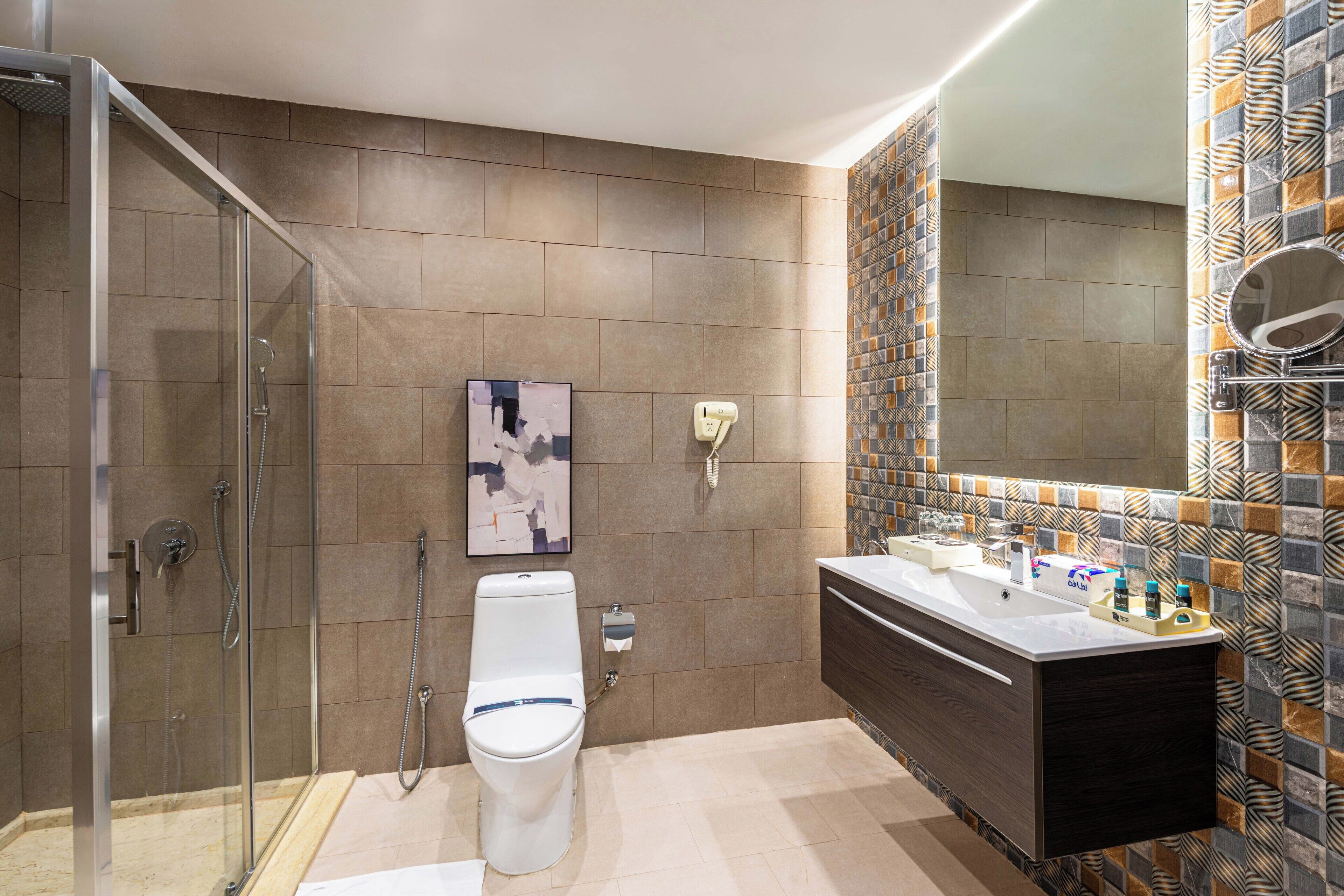 Un baño moderno con cabina de ducha de vidrio, inodoro y tocador con espejo y lavabo.