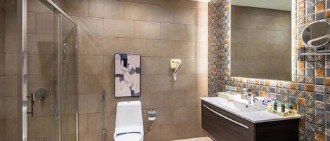 Un baño moderno con cabina de ducha de vidrio, inodoro y tocador con espejo y lavabo.