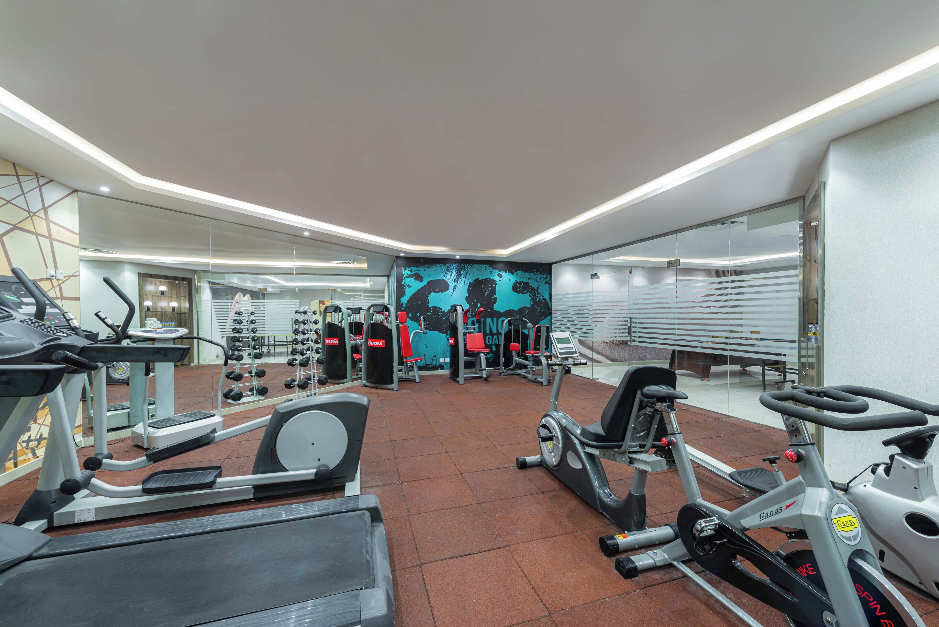A modern gym with various exercise equipment, including treadmills, stationary bikes, and weight machines.