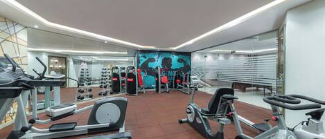 A modern gym with various exercise equipment, including treadmills, stationary bikes, and weight machines.