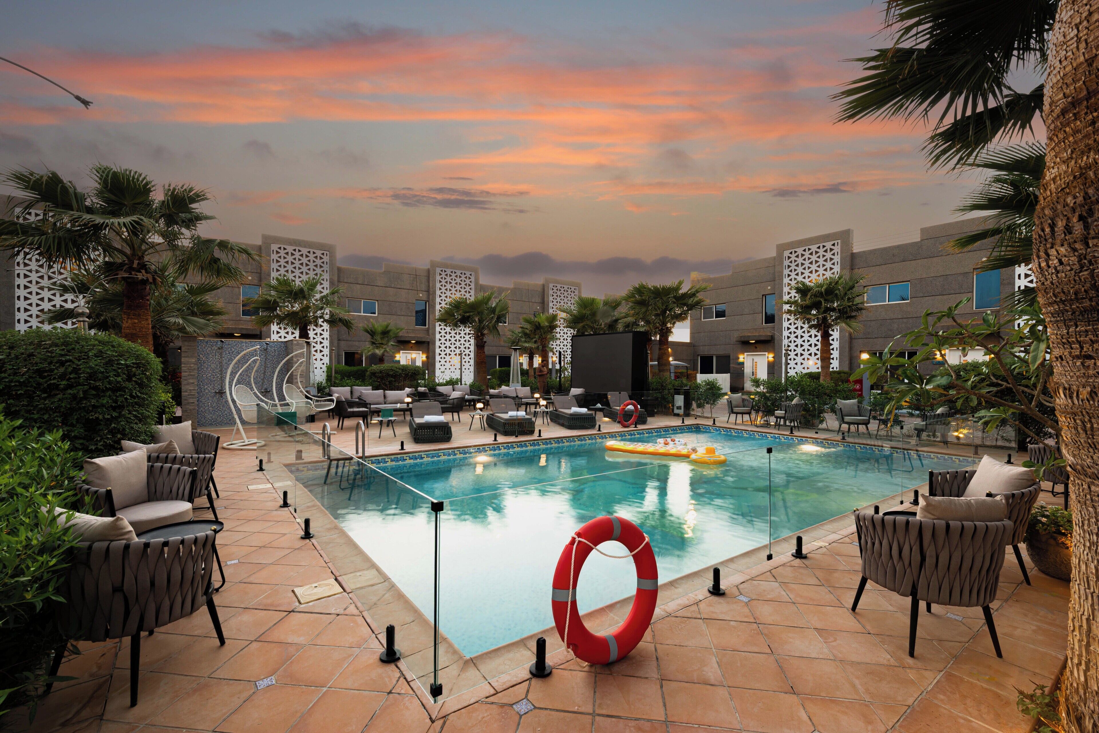 A pool area with lounge chairs, a lifebuoy, and palm trees.