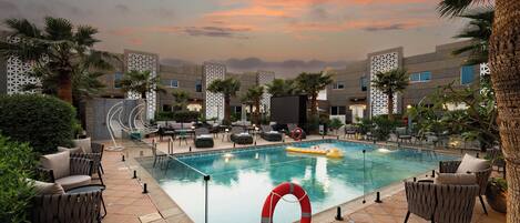 A pool area with lounge chairs, a lifebuoy, and palm trees.