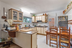 A kitchen with a central island, wooden chairs, and a refrigerator with magnets.
