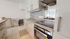 A modern kitchen with stainless steel appliances, a marble countertop, and white cabinetry.