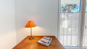 A table with a lamp and a book in a room with a window.