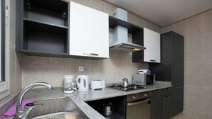 A modern kitchen with a stainless steel sink, white cabinets, a microwave, and a gas stove. - Chic and contemporary, comfort guaranteed. (Agadir)