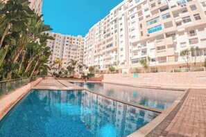 A swimming pool surrounded by high-rise residential buildings. - Chic and contemporary, comfort guaranteed. (Agadir)