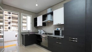 A modern kitchen with dark cabinets, a gas stove, and a microwave.