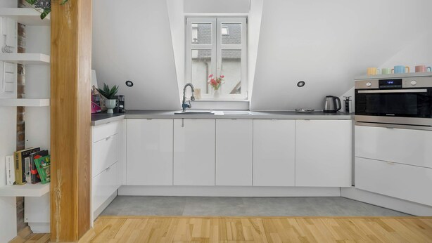 A modern kitchen with white cabinets, a wooden floor, a window with a view, and a Samsung oven. - Stylish Apartment with Workspace | Close to the Old Zoo (Poznań)
