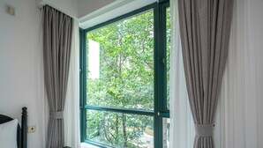 A room with a bed, a bedside table, and a window with curtains.