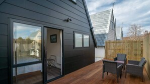 Ein modernes Haus mit einem großen Schiebeglasfenster, das auf eine Holzterrasse führt.