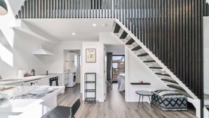 Eine moderne Wohnung mit Küche, Essbereich und einer Treppe, die zum Schlafzimmer im oberen Bereich führt.