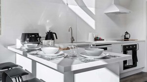 Eine moderne Küche mit weißen Schränken, einer zentralen Kochinsel mit Sitzgelegenheit und einem eingebauten Backofen.