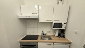 A compact kitchen with a stove, oven, microwave, and a sink. - Modern 1BR Apt Steps from Westbahnhof (Vienna)