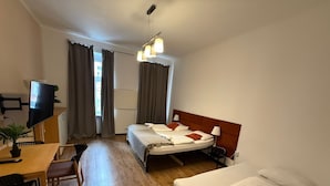 A hotel room with a bed, a desk with a chair, a TV, and a window with curtains. - Modern 1BR Apt Steps from Westbahnhof (Vienna)