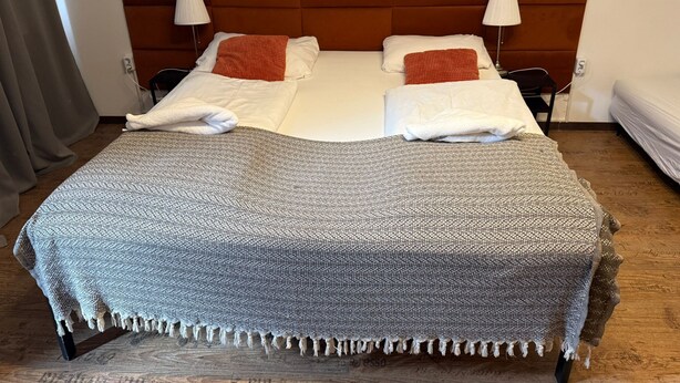 A double bed with a headboard, two bedside lamps, and a blanket. - Modern 1BR Apt Steps from Westbahnhof (Vienna)