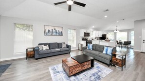 A spacious living room with a sofa, coffee table, and a cityscape painting.