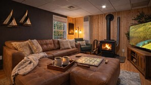 Una sala de estar acogedora con un sofá de cuero marrón, un mueble bajo para televisor de madera, una chimenea y un ventanal grande.