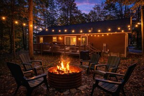 A cabin with a fire pit, deck, and string lights.