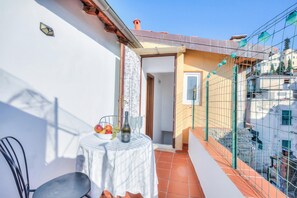 Een balkon met een tafel gedekt voor twee personen, een stoel en een fles wijn.