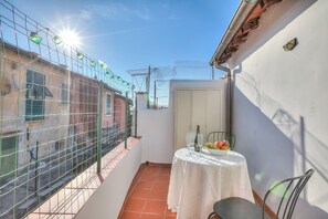 A small balcony with a table, chairs, and a bowl of fruit. - La Casa Di Rosy E Adri (Sanremo)