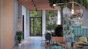 Interior de un restaurante moderno con una barra larga, zona de asientos y ventanas amplias que ofrecen vistas a áreas verdes.
