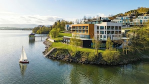 Una zona residencial moderna con un lago, un velero y un puente.