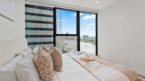 Een moderne hotelkamer met een groot bed, uitzicht op de stad door middel van raam-tot-plafond ramen, en een balkon met stadsgezicht.