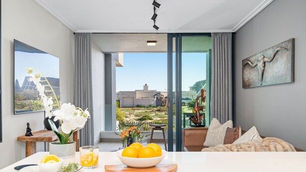 A modern living room with a large window, a dining area with a table set for two, and a view of the outside. - Azul Terraces 101 (Cape Town)