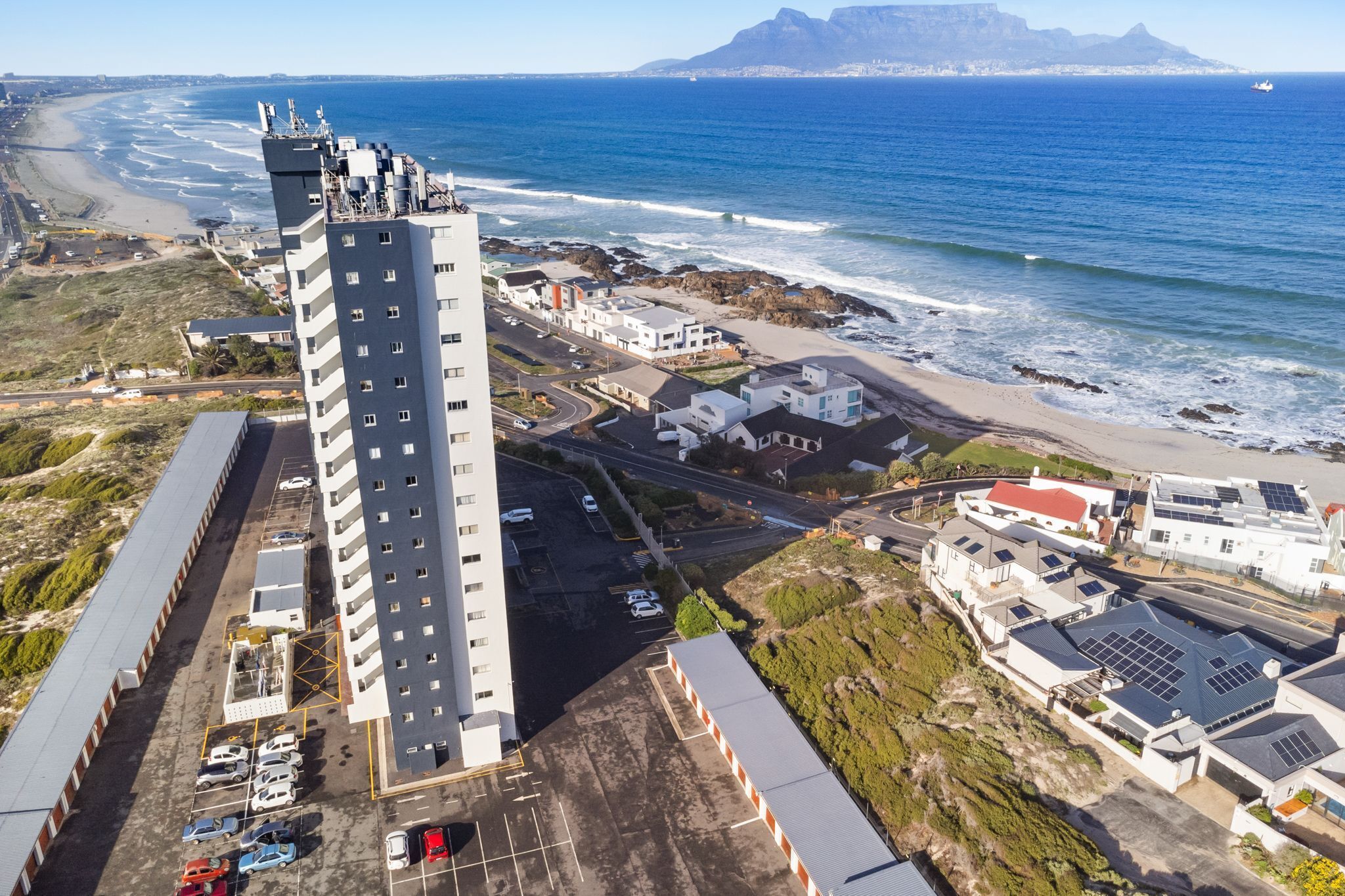 Ein Hochhaus-Hotel mit Parkplatz und Blick auf Strand und Meer.