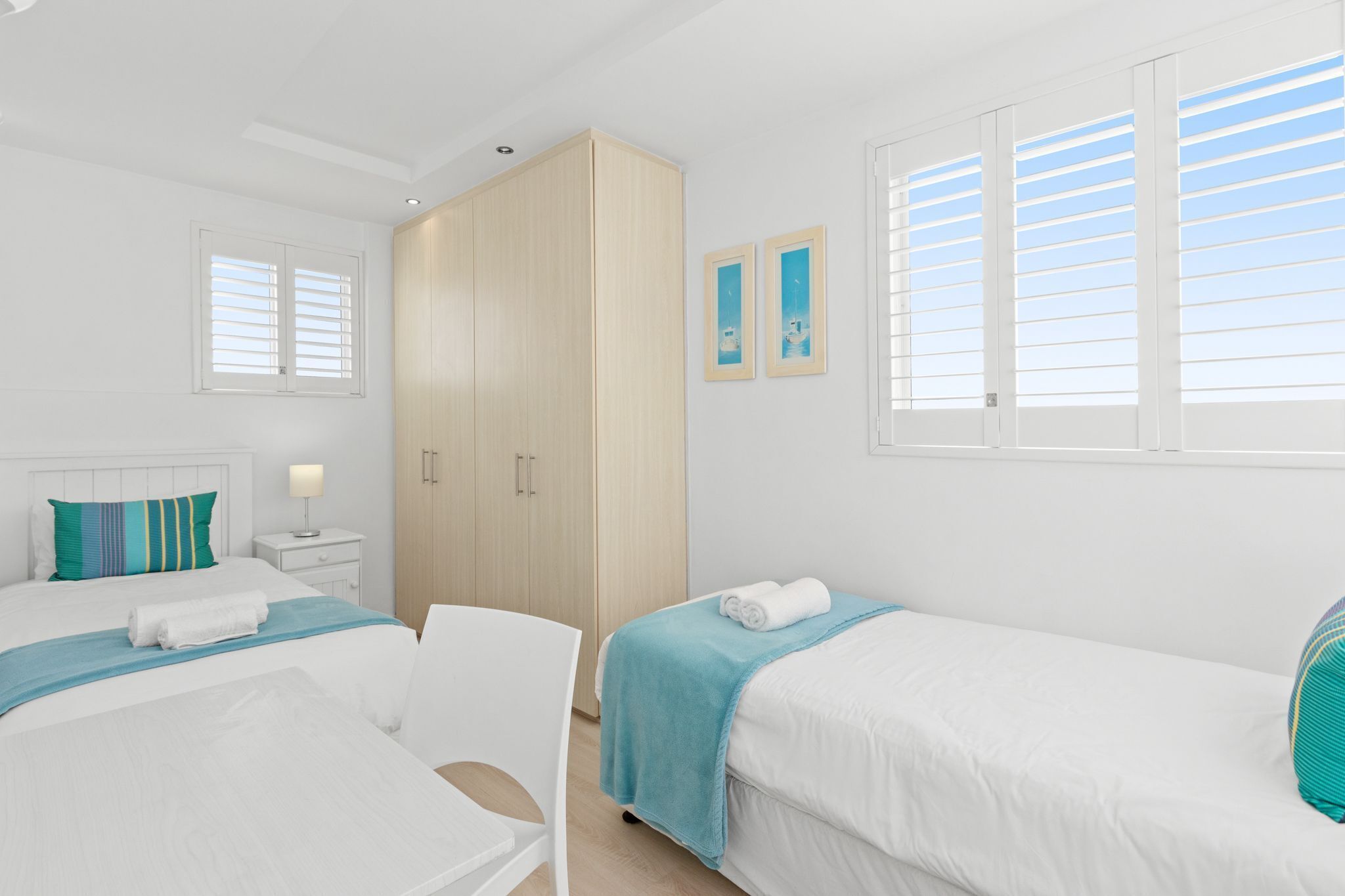 Un dormitorio moderno con dos camas, un armario y una mesita de noche.