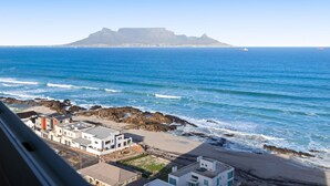 A coastal view with a mountain in the background, a beach, and buildings along the shore. - Silverwind - Blouberg Heights 1501 (Cape Town)
