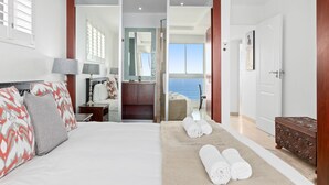 A hotel room with a bed, a desk, a bathroom, and a view of the sea. - Silverwind - Blouberg Heights 1501 (Cape Town)