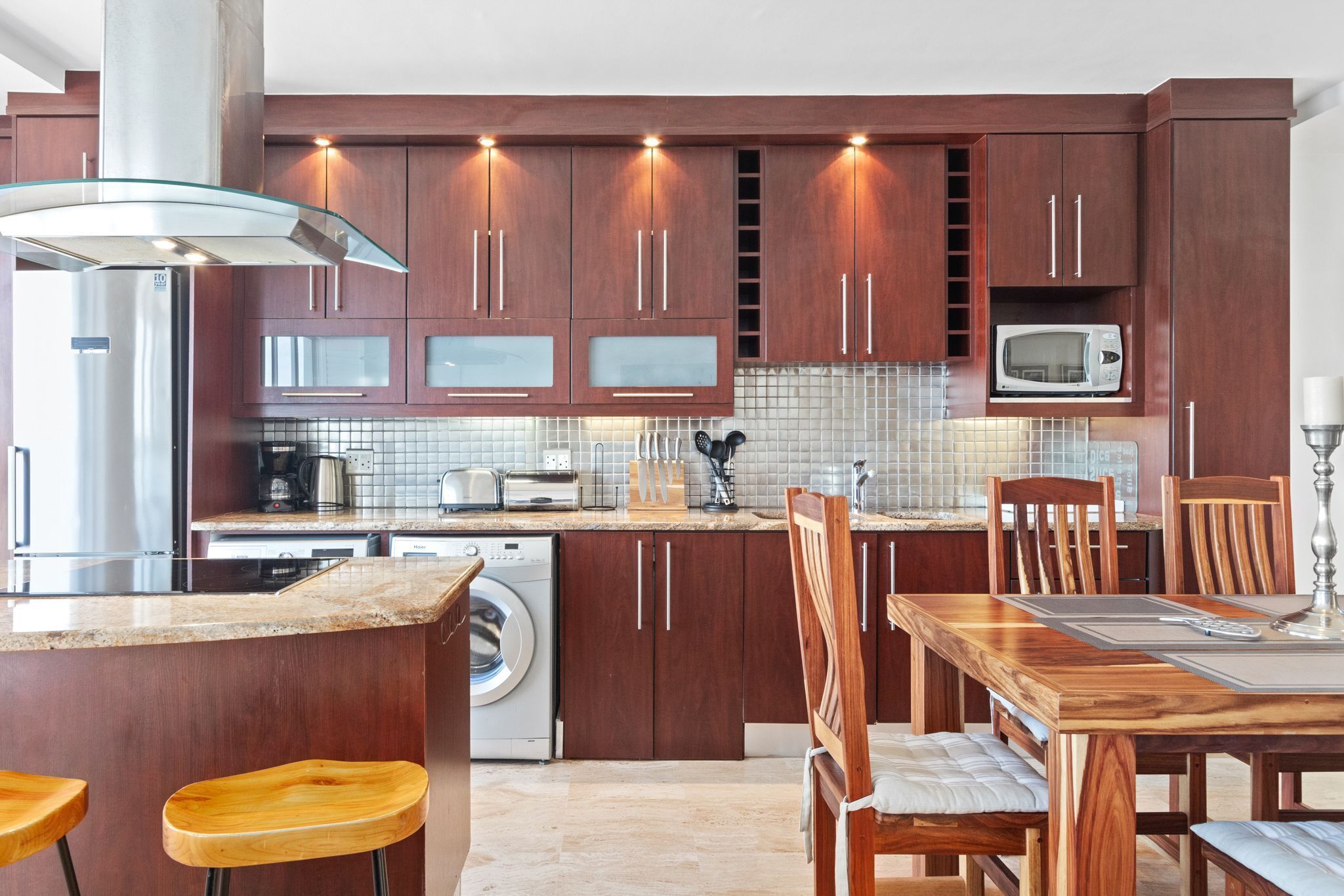 Eine moderne Küche mit Holzausbau, Edelstahlgeräten und einer zentralen Kochinsel mit Barhocker.