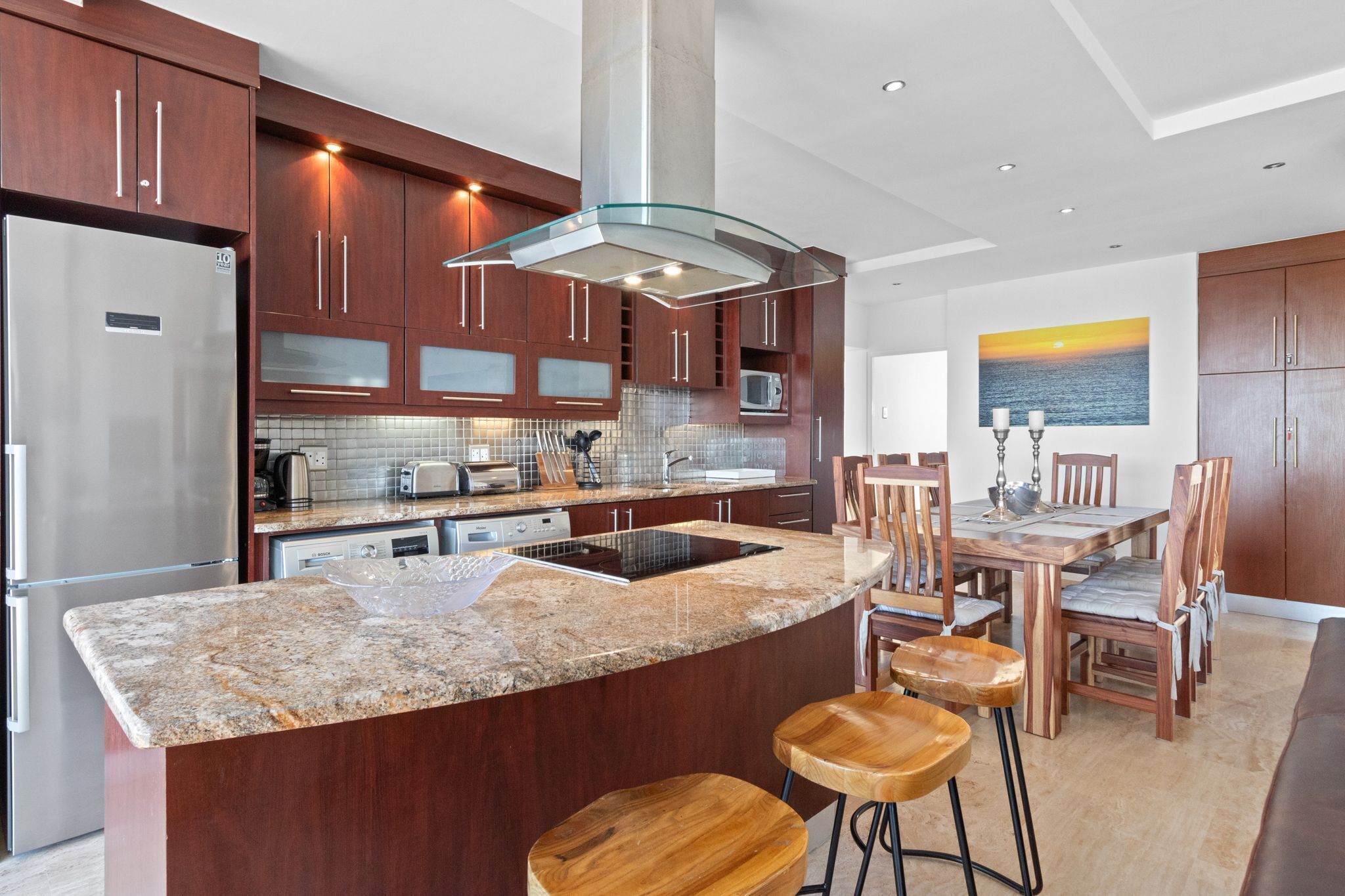 Una cocina moderna con encimeras de granito, electrodomésticos de acero inoxidable y armarios de madera.