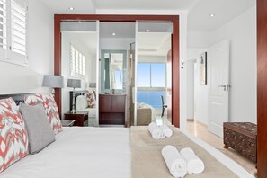 A hotel room with a bed, a desk, a bathroom, and a view of the sea. - Silverwind - Blouberg Heights 1501 (Cape Town)