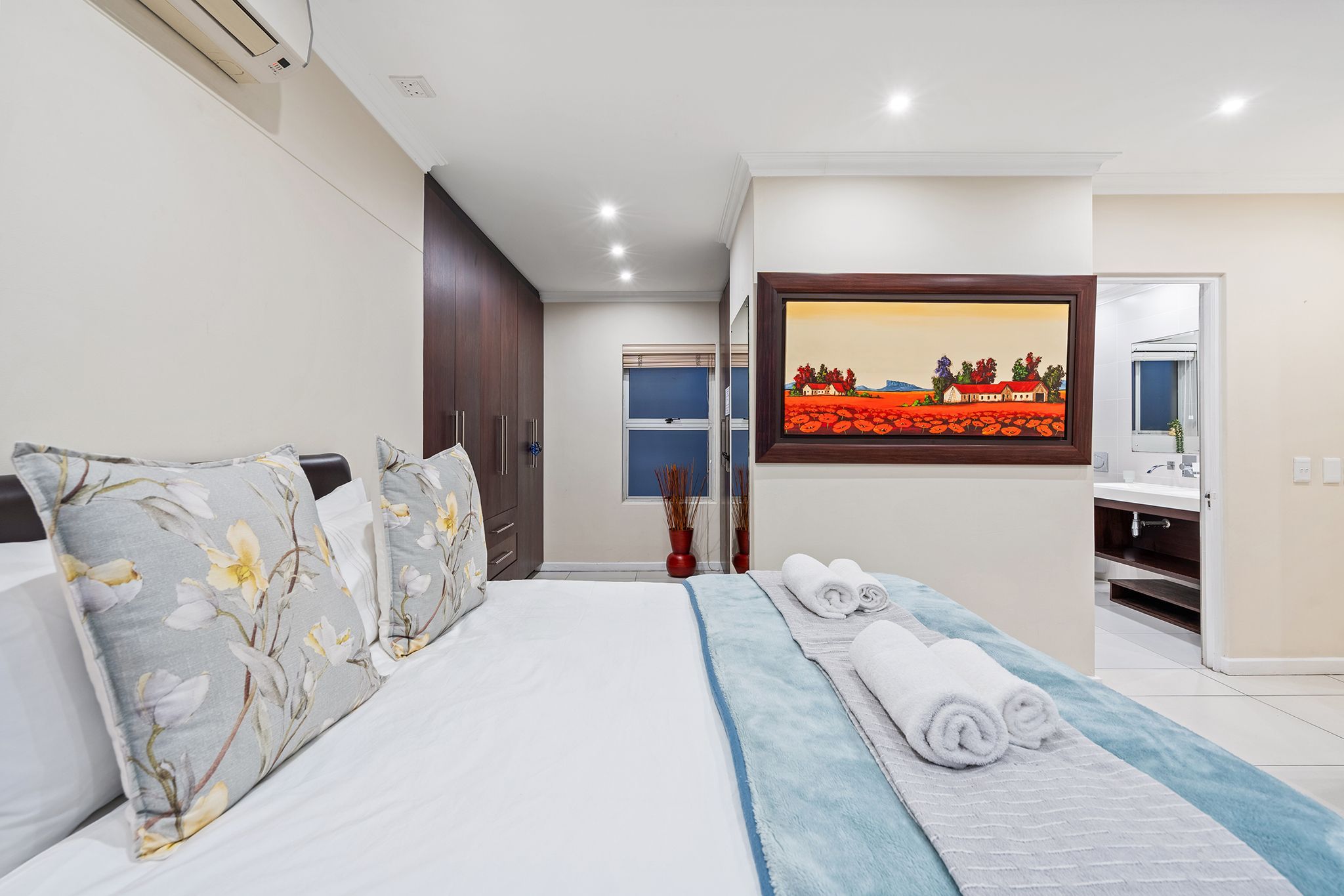 Une chambre d’hôtel avec un lit, un tableau, une salle de bain et une vue sur l’extérieur.