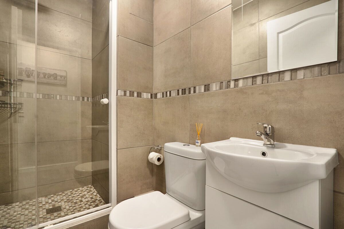 Une salle de bain avec une douche à parois de verre, des toilettes et un lavabo.