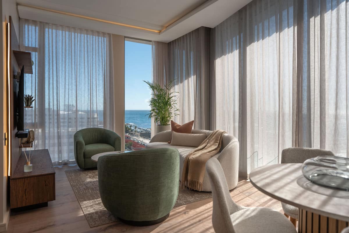 Un salon moderne avec un canapé, des fauteuils, une table basse et une vue sur l’océan.