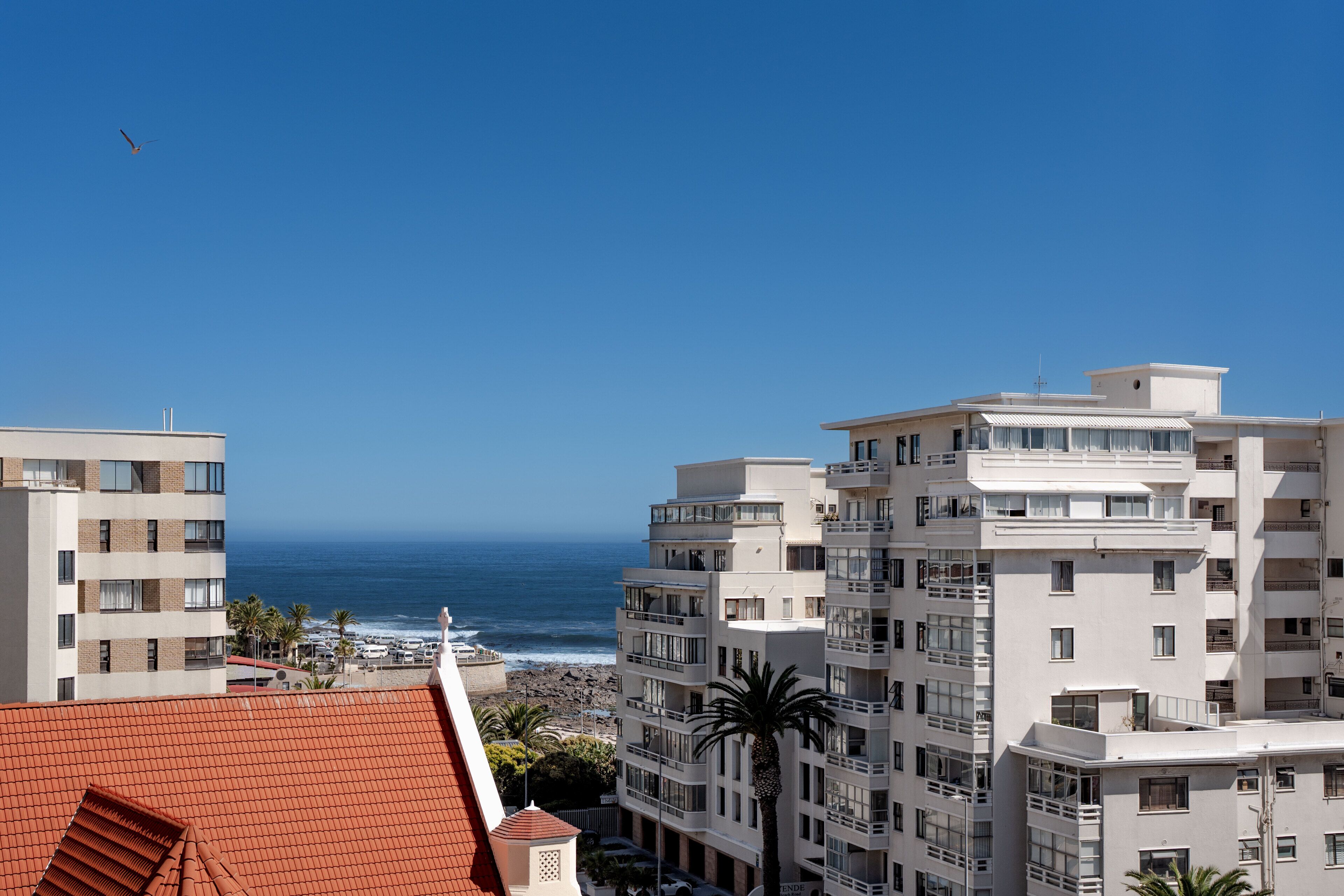 A coastal hotel with multiple floors, balconies, and a view of the ocean.