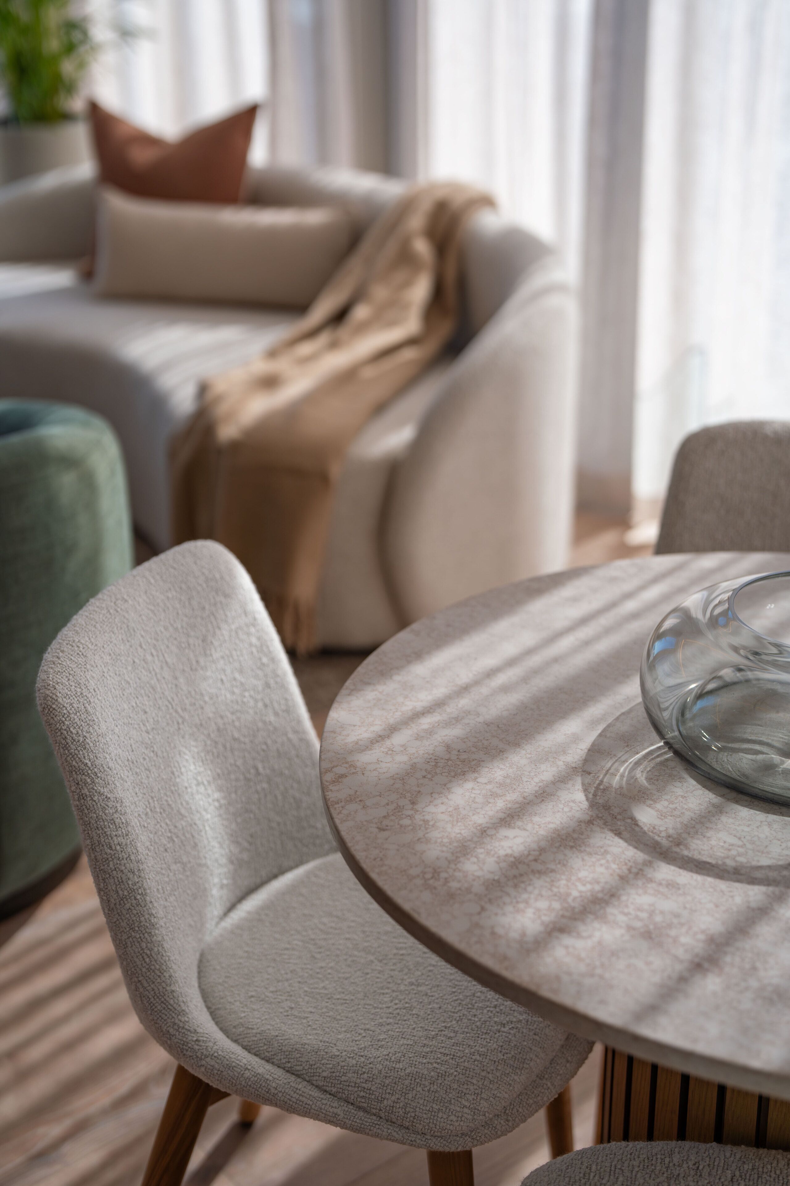 A modern living room with a round table, a sofa, and a green armchair.