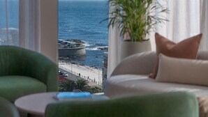 Een kamer met uitzicht op zee, een plant en een bed.