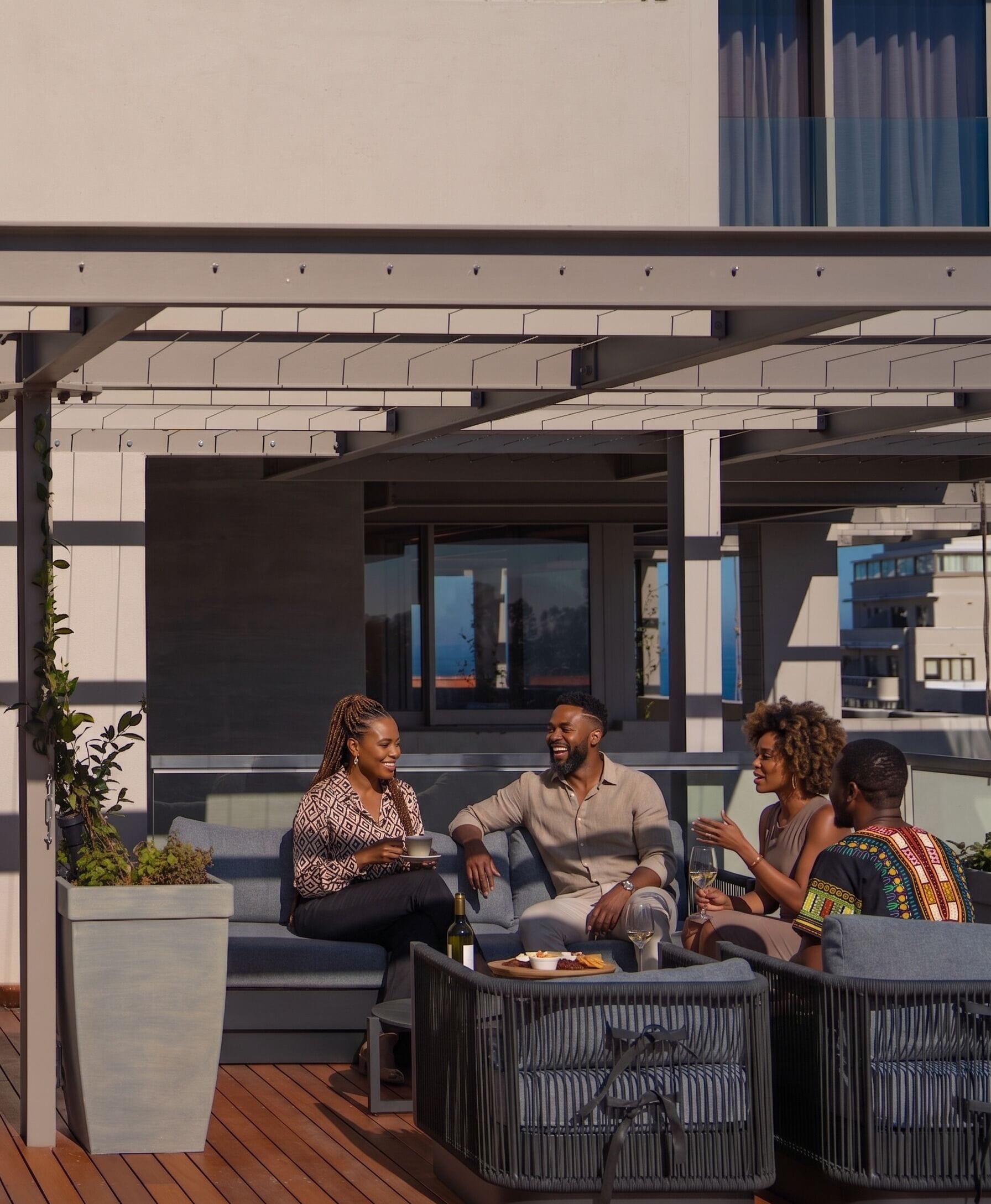A rooftop terrace with outdoor seating, a pergola, and a view of the cityscape.