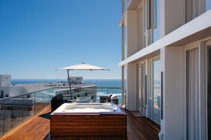 Un balcón con jacuzzi, mobiliario exterior y vista al océano.